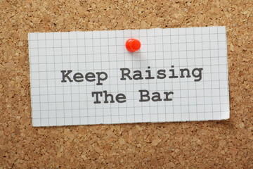 The phrase Keep Raising the Bar on a piece of graph paper