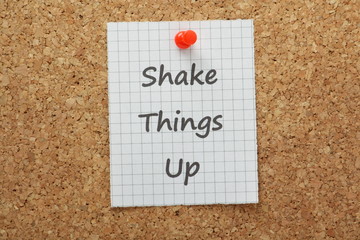 The phrase Shake Things Up on a cork notice board