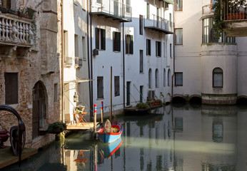 Fototapeta na wymiar Little Boat Docked Among Houses in Treviso, Italy