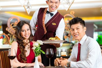 Chinese waiter serving dinner in elegant restaurant or Hotel