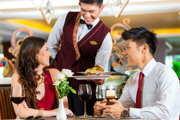 Serveur chinois servant le dîner dans un élégant restaurant ou hôtel
