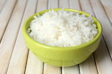 Cooked rice in bowl on wooden background