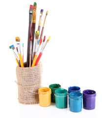 Brushes with paints in vase isolated on white