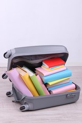 Books in suitcase on wall background