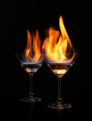 Glasses with burning alcohol on black background