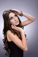 Beautiful young woman with long hair on grey background