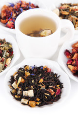 Cup of tea with aromatic dry tea in bowls close up