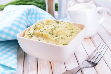 Delicious mashed potatoes with greens in bowl on table close-up