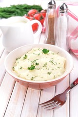 Delicious mashed potatoes with greens in bowl on table close-up