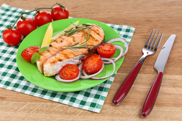 Tasty grilled salmon with vegetables, on wooden table
