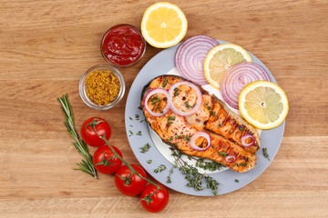 Tasty grilled salmon with vegetables, on wooden table