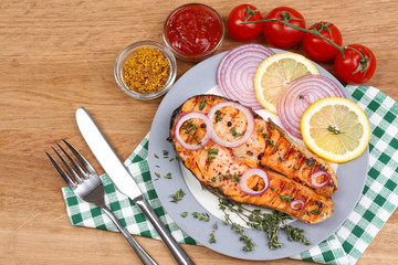 Tasty grilled salmon with vegetables, on wooden table