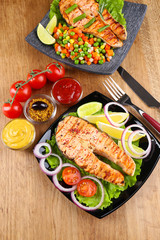 Tasty grilled salmon with lemon and vegetables, on wooden table