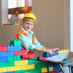 Happy boy in safety helmet playing indoors building house