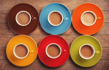 Six color cups of coffee on wooden table.