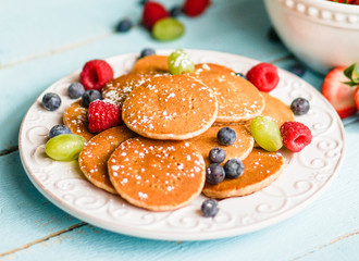 Pancakes with berries on wooden background