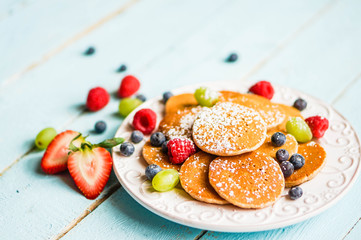 Pancakes with berries on wooden background