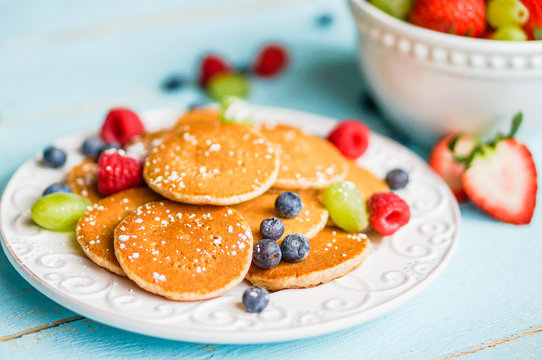 Pancakes with berries on wooden background