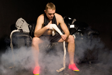 Boxer bandaging his hands in a smoky room
