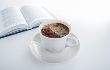 cup of coffee with open book on white