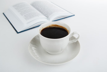 cup of coffee with open book on white