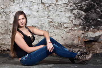 Long-haired young woman at old stone wall