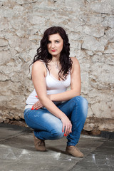 Long-haired young woman at old stone wall