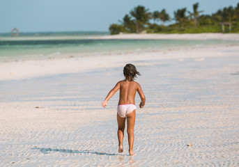 Fototapeta premium Little child running to the ocean and having fun at the beach