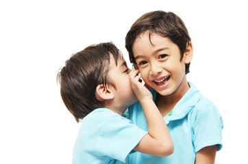 Little sibling boys sharing a secret on white background