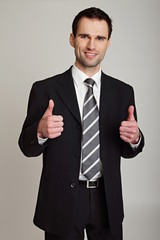 Handsome smiling businessman showing thumbs up