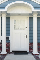 White front door of a classical blue and brick home