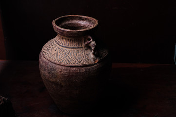 Earthenware jug standing on dark room