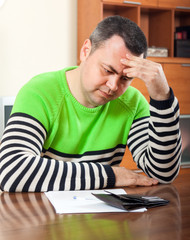 frustrated man at  table with  wallet and documents