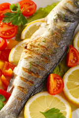 Delicious grilled fish on plate on table close-up