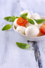 Tasty mozzarella cheese with basil and tomatoes in bowl,