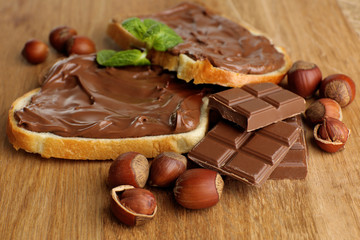Bread with sweet chocolate hazelnut spread on wooden background