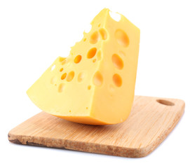 Piece of cheese on plate, on wooden board, isolated on white