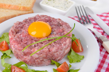 Delicious steak tartare with yolk on plate on table close-up
