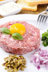 Delicious steak tartare with yolk on plate on table close-up