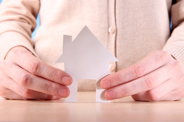 Little paper house in hand close-up, on light background