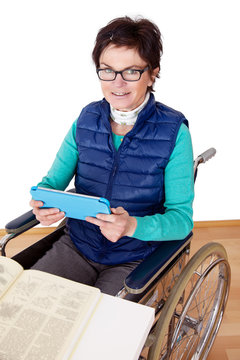 Woman with Tablet PC's in a wheelchair at the table