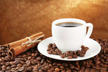 Coffee beans and cup of coffee on table on brown background