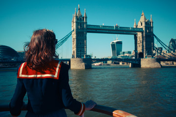 Young woman on boat looking at Tower Bridge in London