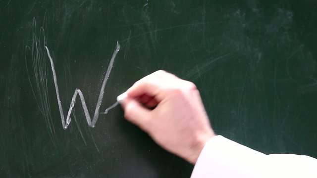 Eine M&auml;nnerhand schreibt Was auf eine Tafef