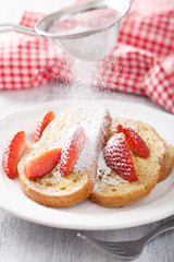 dusting powder sugar over french toast with strawberry