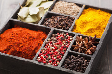 spices in box: pink and black pepper, ground paprika, curry, ani