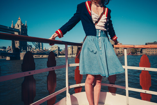 Young woman on the deck of ship with skirt blowing in the wind