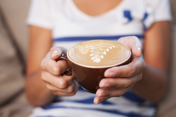 Closeup of woman holding cup with cappuccino coffee 