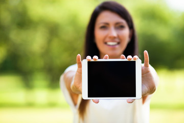 Woman showing tablet outdoors