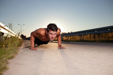 fitness man exercising push ups during sunset